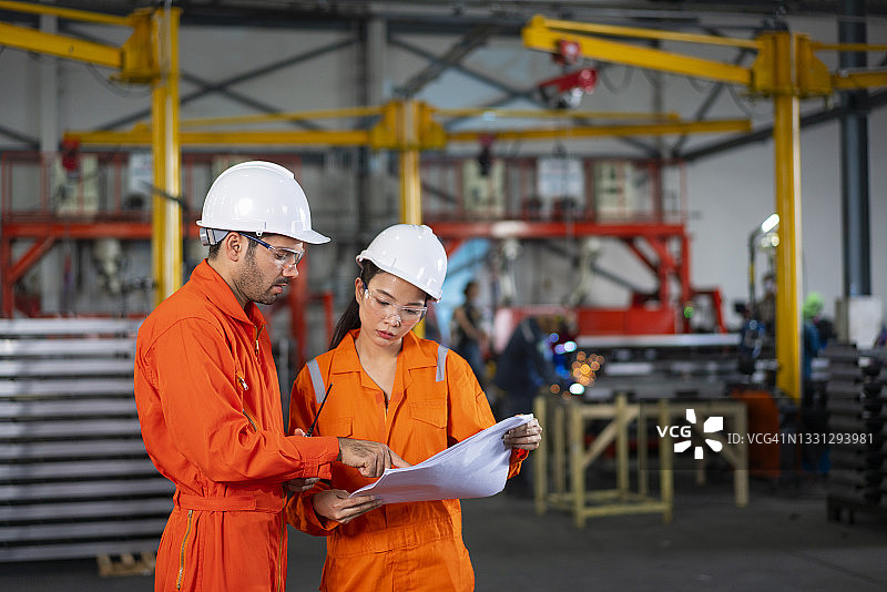 工厂里使用笔记本电脑工作的工业中年男女工程师肖像图片素材