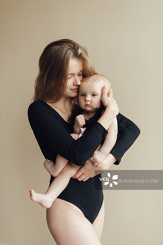 金发碧眼的欧洲女孩和女儿在米色墙壁背景前玩耍图片素材