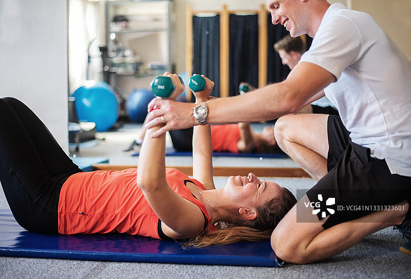 理疗师帮助患者在诊所举重图片素材