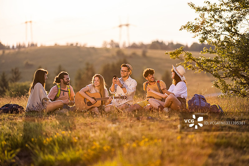 快乐的徒步者在山丘上弹吉他唱歌图片素材