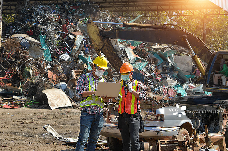 两名工人在泰国废金属堆场看笔记本电脑图片素材