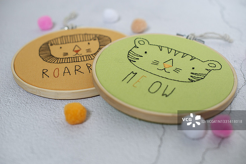 桌子上带有狮子和猫脸图案的两个刺绣绷图片素材