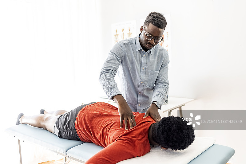 脊椎按摩师在医院按摩床上为女性按摩背部图片素材