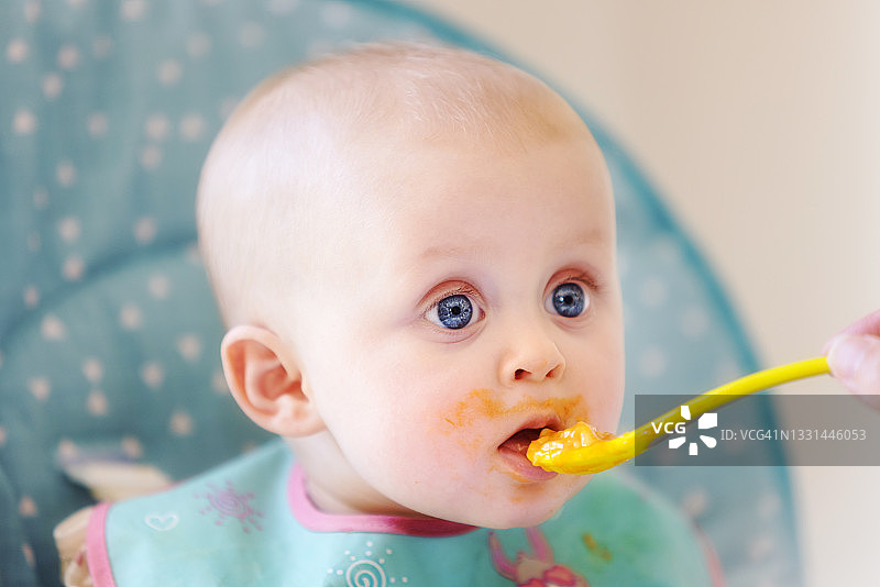 可爱的女婴坐在高脚椅上享受喂食和饮水图片素材