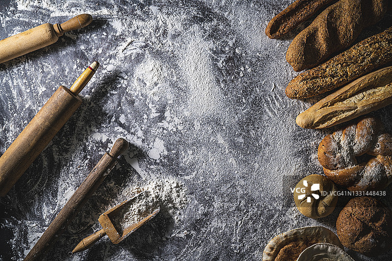 面粉背景上的面包框架，带有擀面杖和各种面包，留有文案空间图片素材