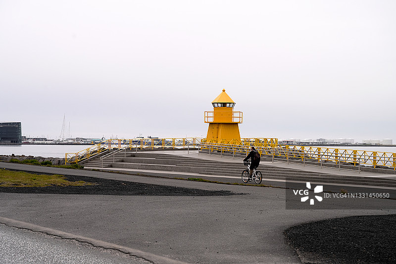 一位女士在市中心灯塔前骑自行车图片素材