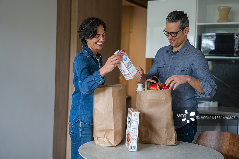 快乐的夫妇从超市购物后带着一袋杂货回家图片素材
