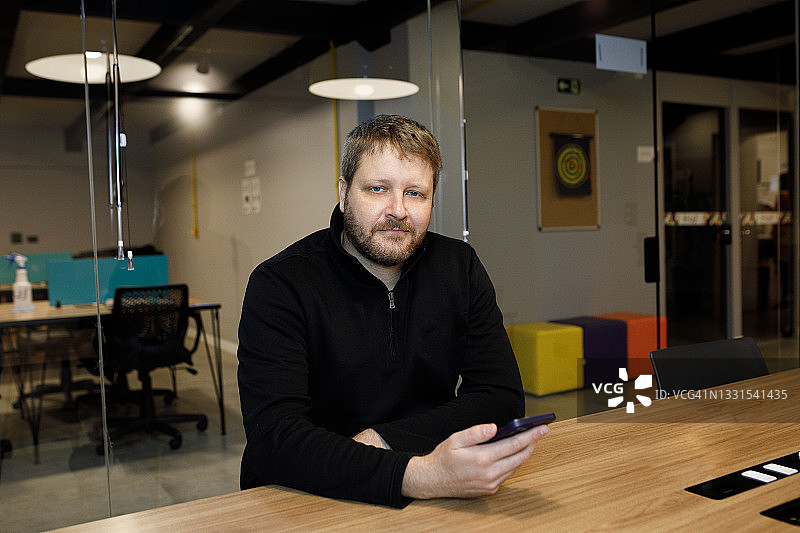 自信的男人看着镜头使用手机图片素材