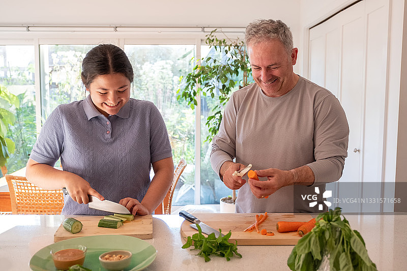 快乐的欧亚混血女儿和父亲准备纯素沙拉卷食材图片素材