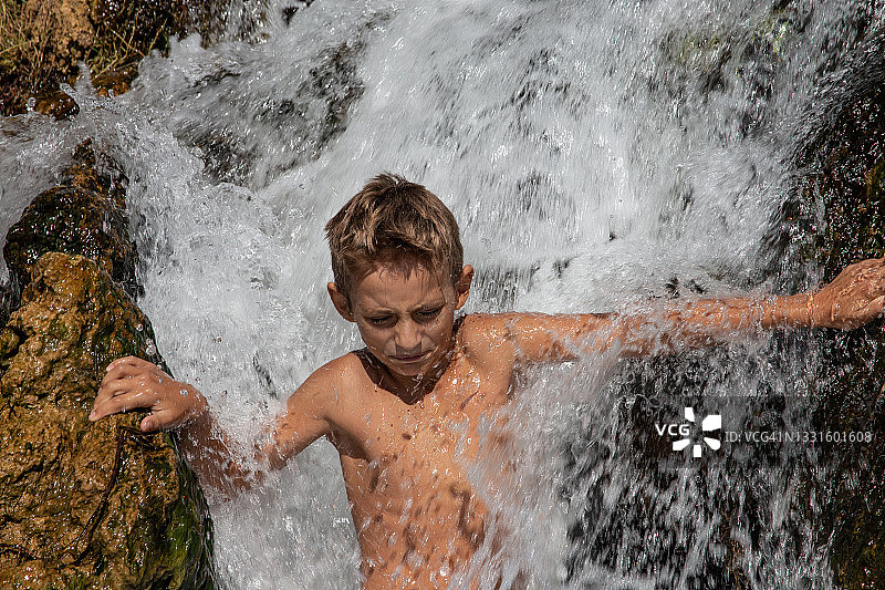 站在瀑布里的小男孩图片素材