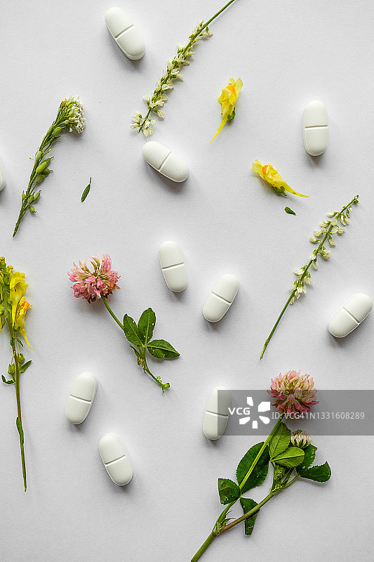 鲜花与草药：白色背景，草本有机天然药片与胶囊。替代医学、保健与顺势疗法概念，疾病的治疗与预防、药物服用。图片素材