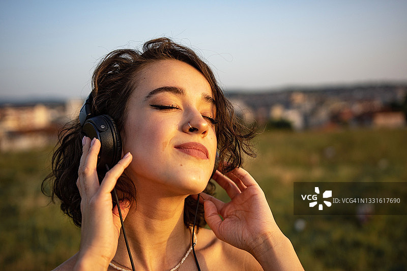 平静的女人戴着耳机在户外听音乐图片素材