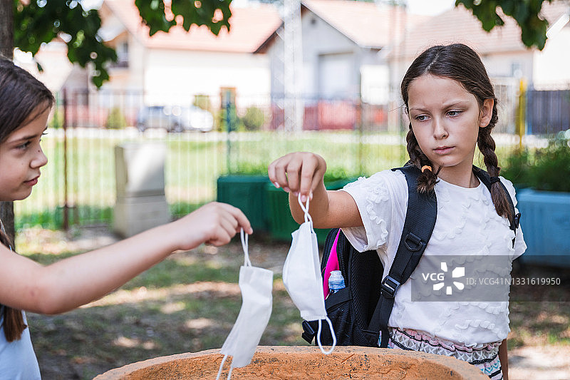 学生将防护口罩放入垃圾桶图片素材