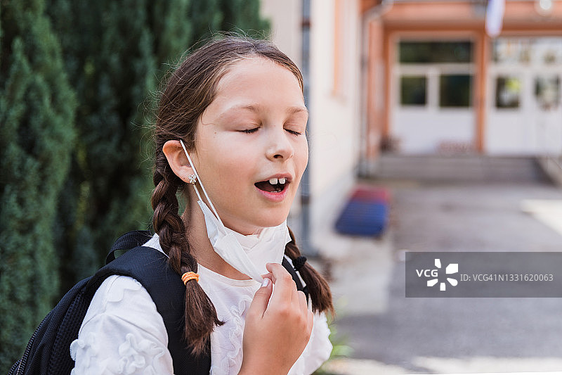 孩子放学后摘下口罩，感到轻松图片素材