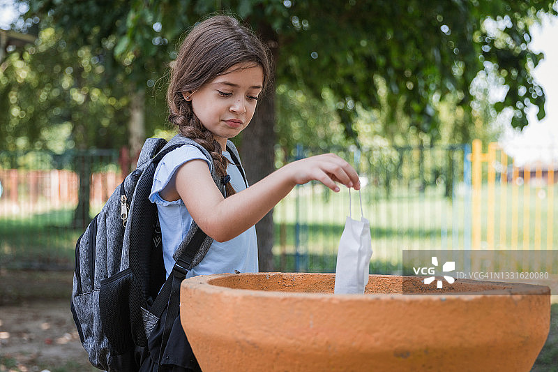做鬼脸并扔掉防护口罩的女学生图片素材