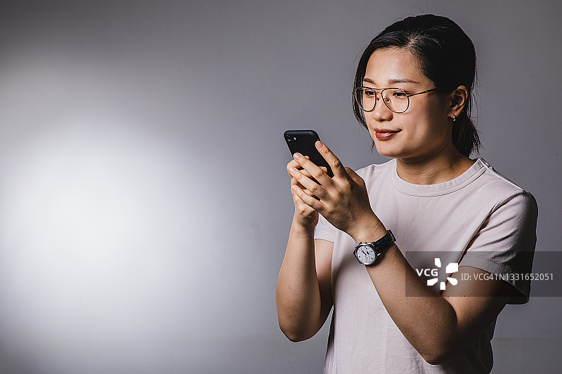 亚洲女性使用手机的摄影棚肖像拍摄图片素材