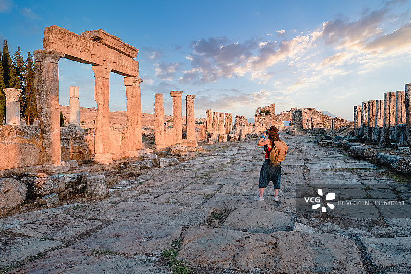 女游客在希拉波利斯古城弗朗提努斯门前拍照，棉花堡图片素材
