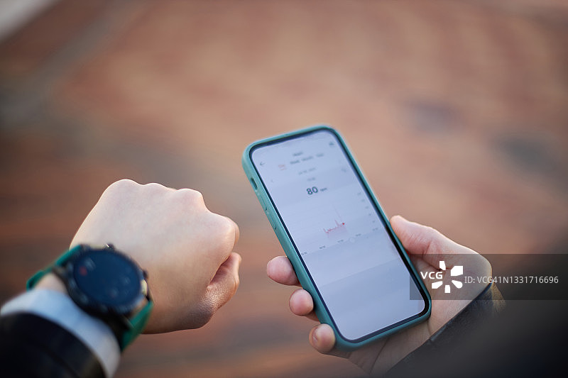 查看智能手表和智能手机以获取健康信息的亚洲男人图片素材