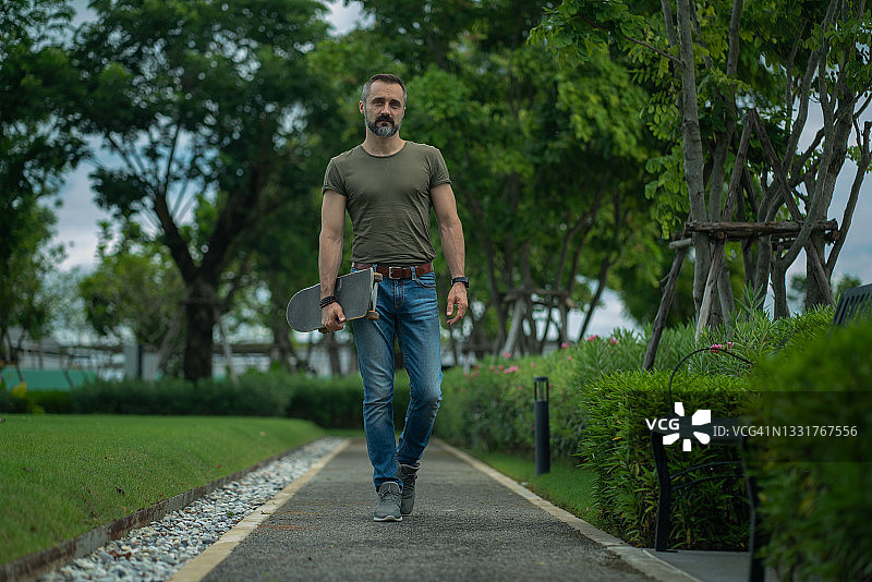 生活方式：留胡子的男人在公园滑板图片素材