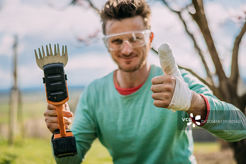 男人拿着电动理发器，展示受损的竖起大拇指图片素材