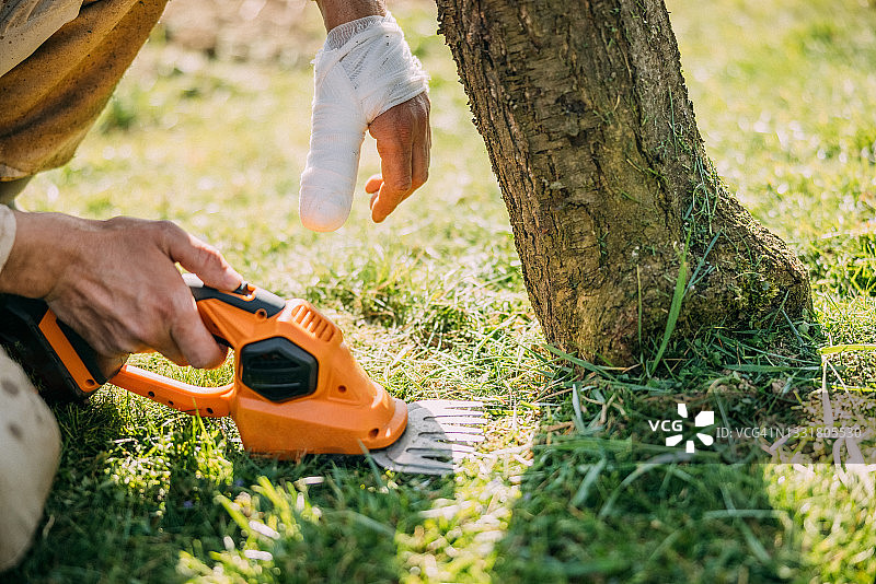 男人用电动修剪机割草图片素材