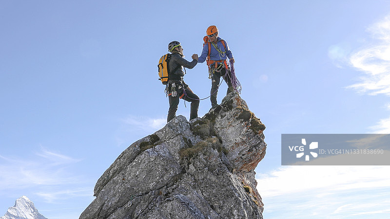登山者在山顶峰击掌庆祝图片素材