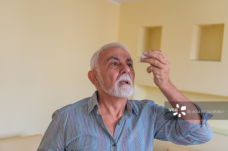 一位患有眼疾的老年人正在滴眼药水图片素材