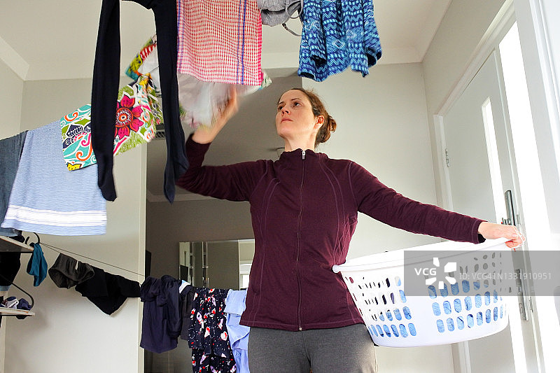 在室内晾晒湿衣服的女人图片素材