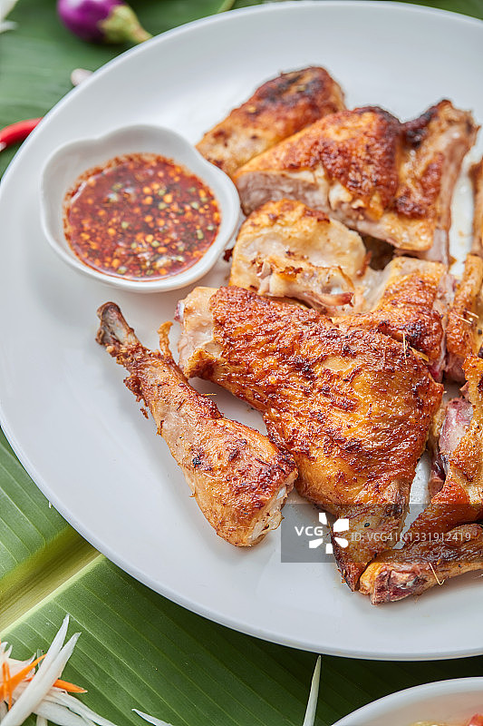 烤鸡搭配香辣蘸酱，白色餐盘盛装图片素材