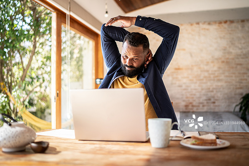在家工作的中年男人伸展身体图片素材