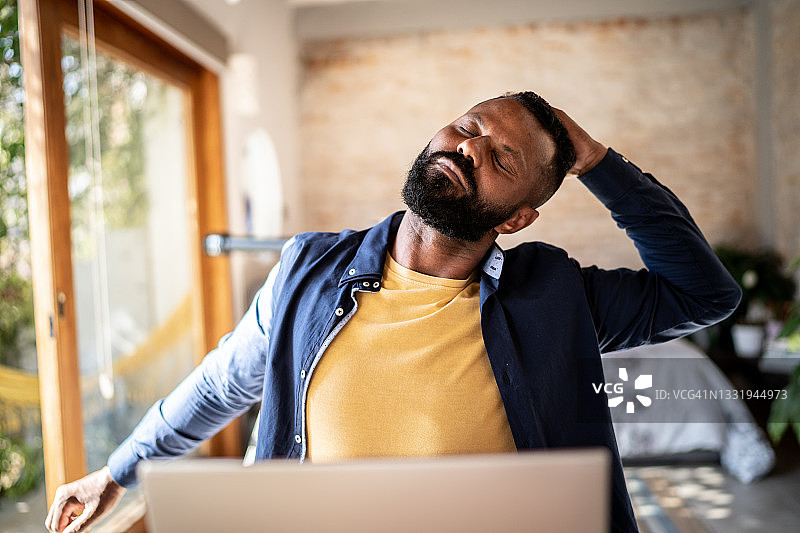 在家工作的中年男人伸展身体图片素材