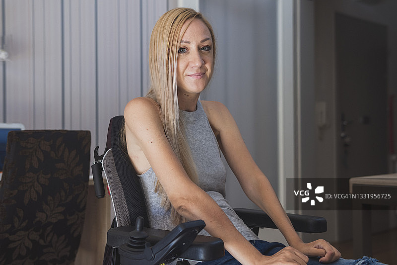 一位坐在轮椅上的美丽年轻残疾妇女在她的公寓里图片素材