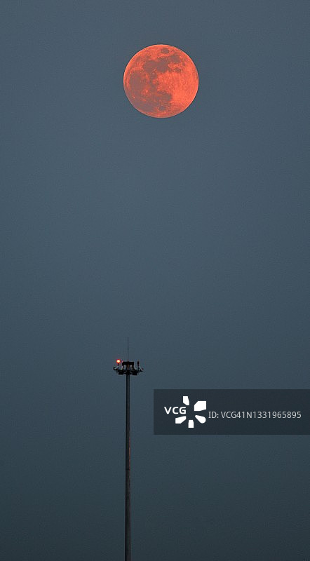 红色满月升起，地面上的街灯亮起图片素材