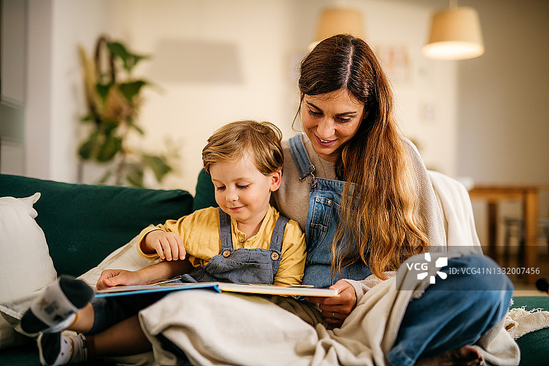 可爱的小男孩和年轻母亲一起阅读图画书图片素材