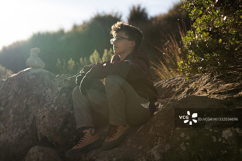 男孩坐在岩石上眺望冬日山景图片素材