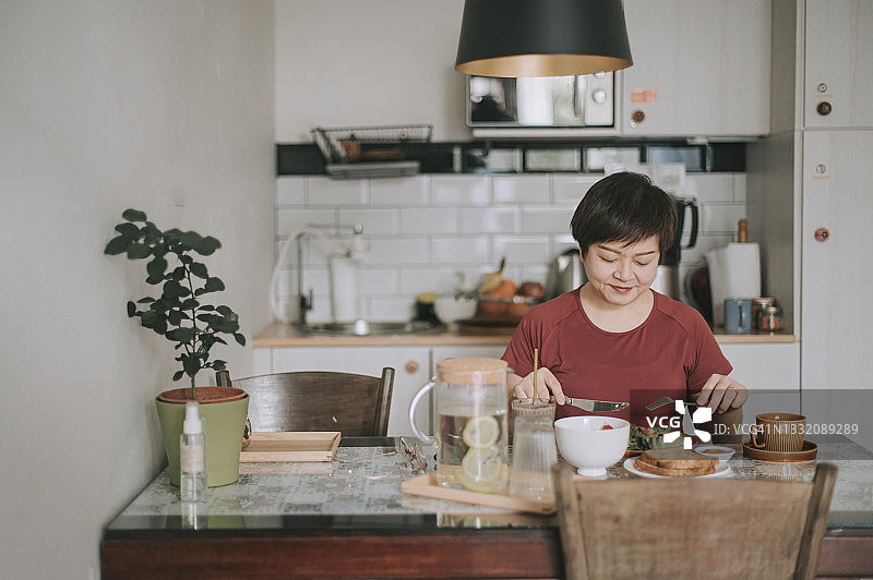 在餐桌旁享用健康沙拉早餐的亚洲女性图片素材