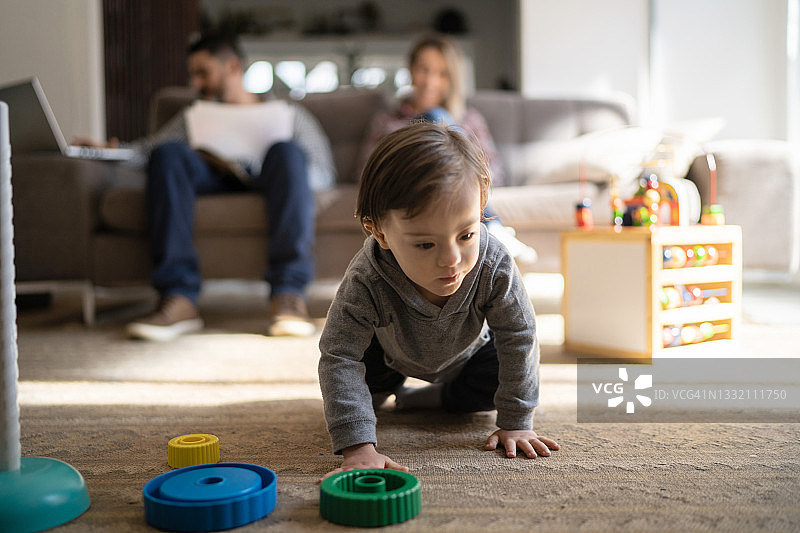 男孩在家玩耍，父母在背景中图片素材