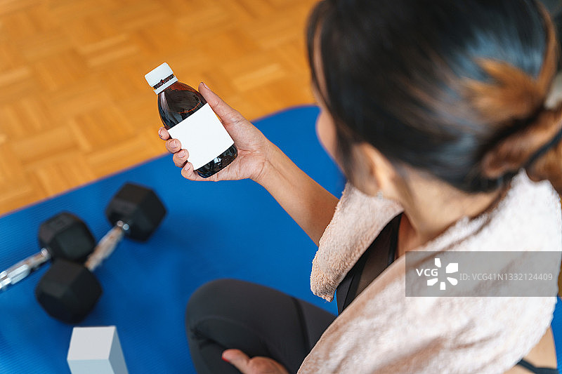 40多岁的亚洲女性在锻炼期间服用膳食补充剂图片素材