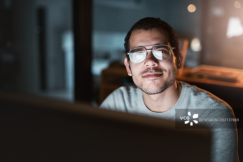 晚上坐在办公室书桌前使用电脑的年轻男子肖像图片素材