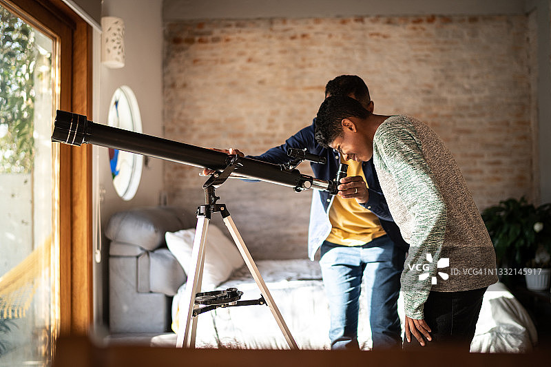 父子在家用望远镜观星图片素材