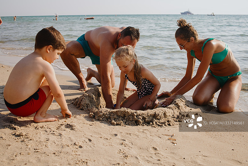 兄妹在沙滩上堆沙堡图片素材