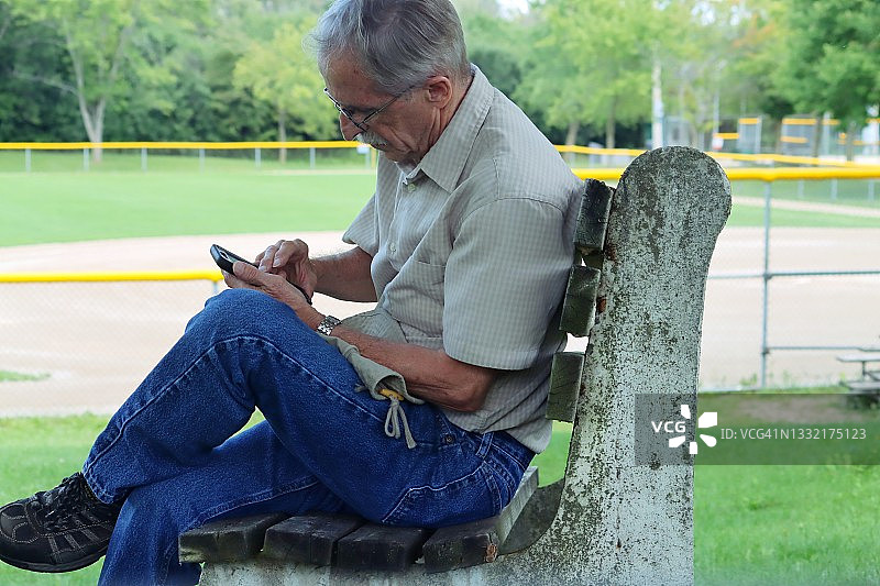 在长凳上玩手机的男人图片素材