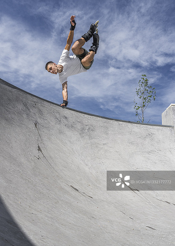 阳光明媚的日子里在运动坡道上做特技的年轻男人图片素材