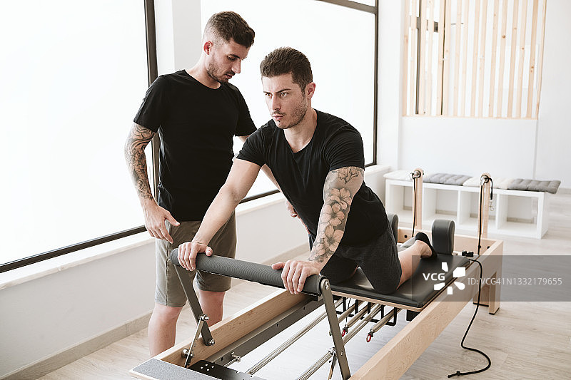 男教练指导男子在普拉提馆锻炼图片素材
