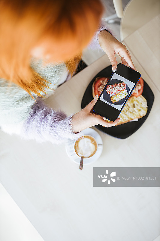 红发女人在自助餐厅拍摄三明治图片素材