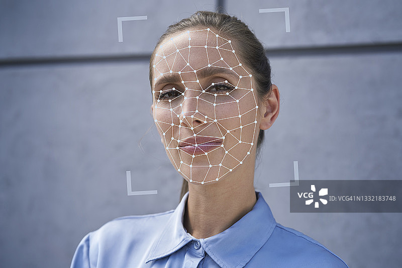在墙前进行面部识别生物识别的女商人图片素材