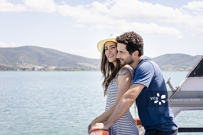 阳光明媚，情侣依偎在游船栏杆旁图片素材