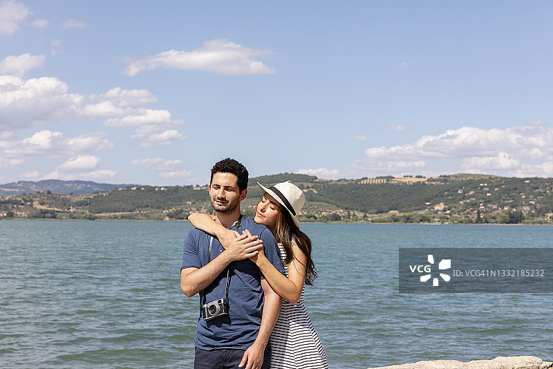 在特拉西梅诺湖前，女人从背后拥抱男友图片素材