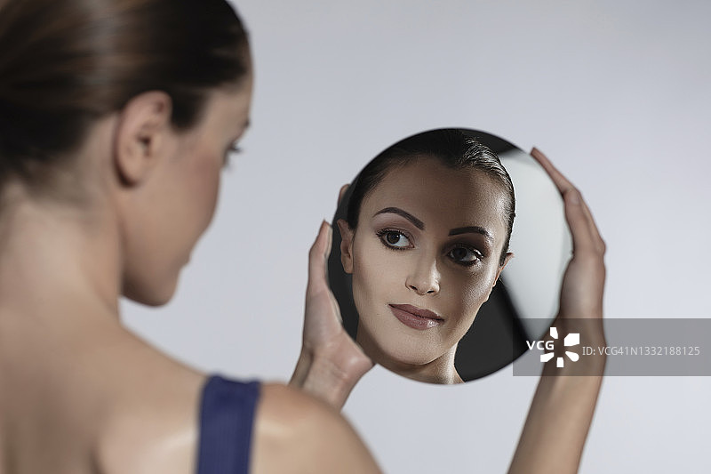 女人看着白色背景上的镜子图片素材