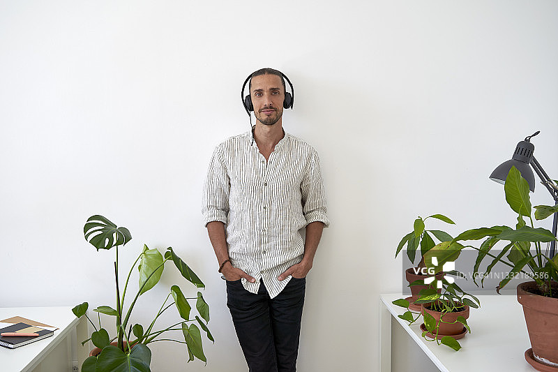 戴着耳机靠在办公室墙上的男客服代表图片素材